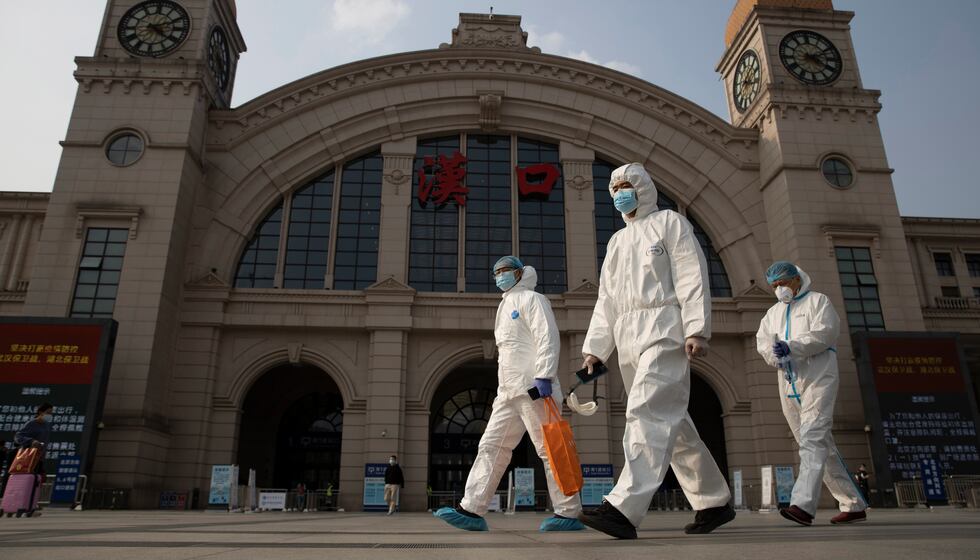 FILE - In this April 7, 2020 file photo, workers in protective overalls walk past the Hankou...